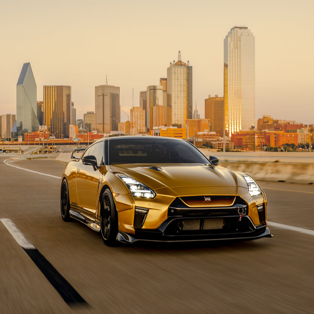 Gold sports car driving on a road with a city skyline in the background